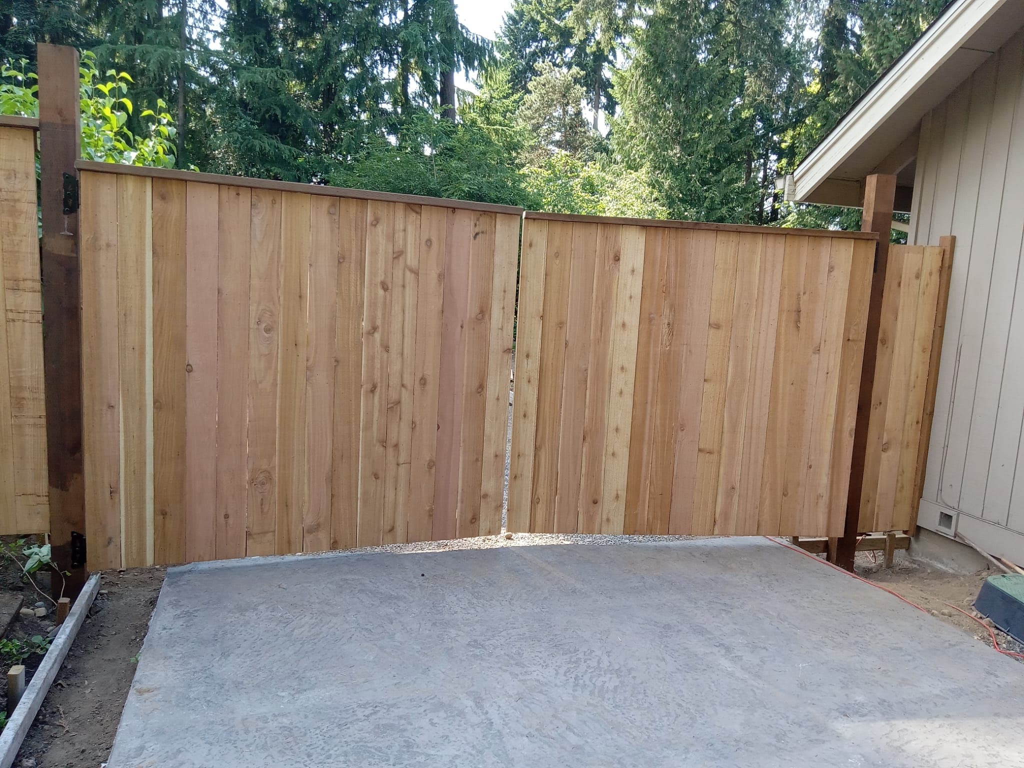 Custom cedar double gate with concrete pad at residential property
