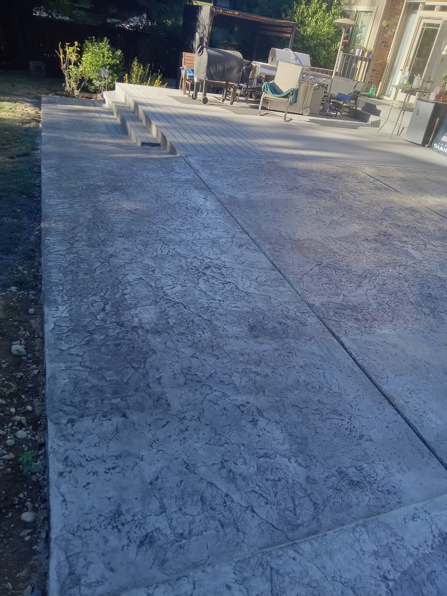 Large stamped concrete patio with steps and outdoor furniture